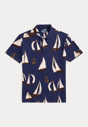 Polo bleu marine avec des motifs de voiliers blancs et d'ancres marron sur le tissu, doté d'un col et d'une patte à trois boutons.