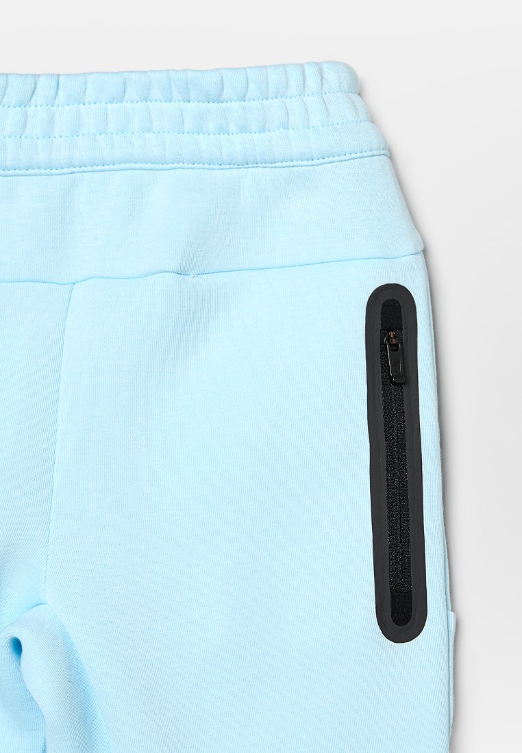 Pantalons de jogging bleu clair avec taille élastique, dotés d'une poche zippée noire sur le côté et d'une texture de tissu lisse et douce.