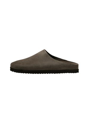 Chausson d'intérieur en daim marron doux, type slip-on, avec semelle en caoutchouc noir et talon ouvert pour un port facile à l'intérieur.