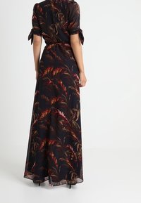 Květinové maxi šaty, černá látka s barevnými vzory listů, krátké rukávy se šněrováním, upnutý pas, splývavá sukně až ke kotníkům.
