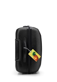 Zwarte harde koffer met een gestructureerde oppervlakte, een zijklep, dubbele ritsen en een kleurrijke ananas bagagelabel eraan bevestigd.