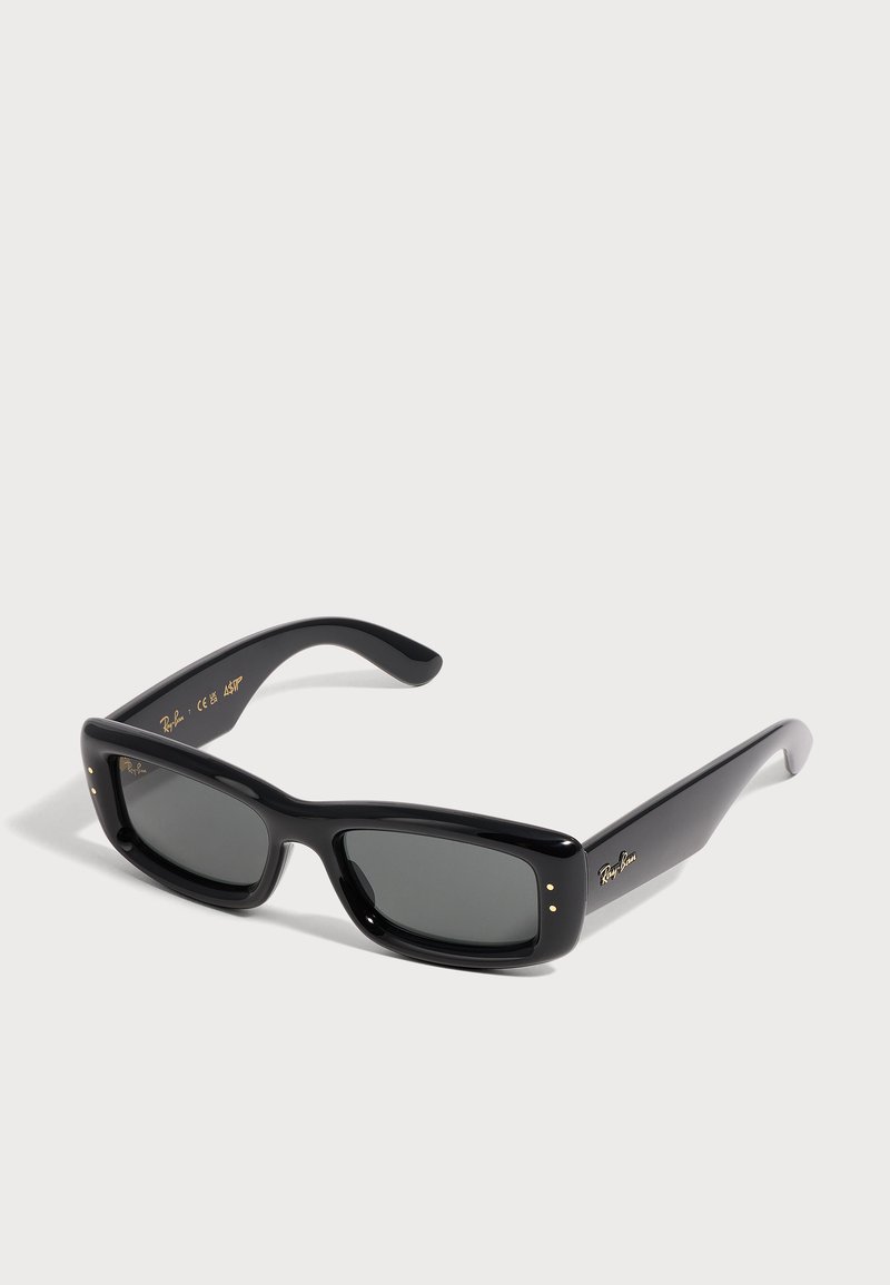 Μαύρα ορθογώνια γυαλιά ηλίου Ray-Ban με παχιά σκελετά και σκούρους φακούς, εμφανίζονται σε απλό ανοιχτό φόντο.