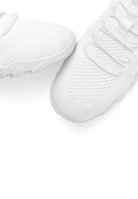 White athletic shoes with a mesh upper, round toe, and textured design. Laces and a cushioning sole feature prominent accents.