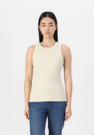 Débardeur beige à côtes avec encolure ronde et larges bretelles, silhouette ajustée associée à un jean bleu. Texture unie, sans motifs visibles.