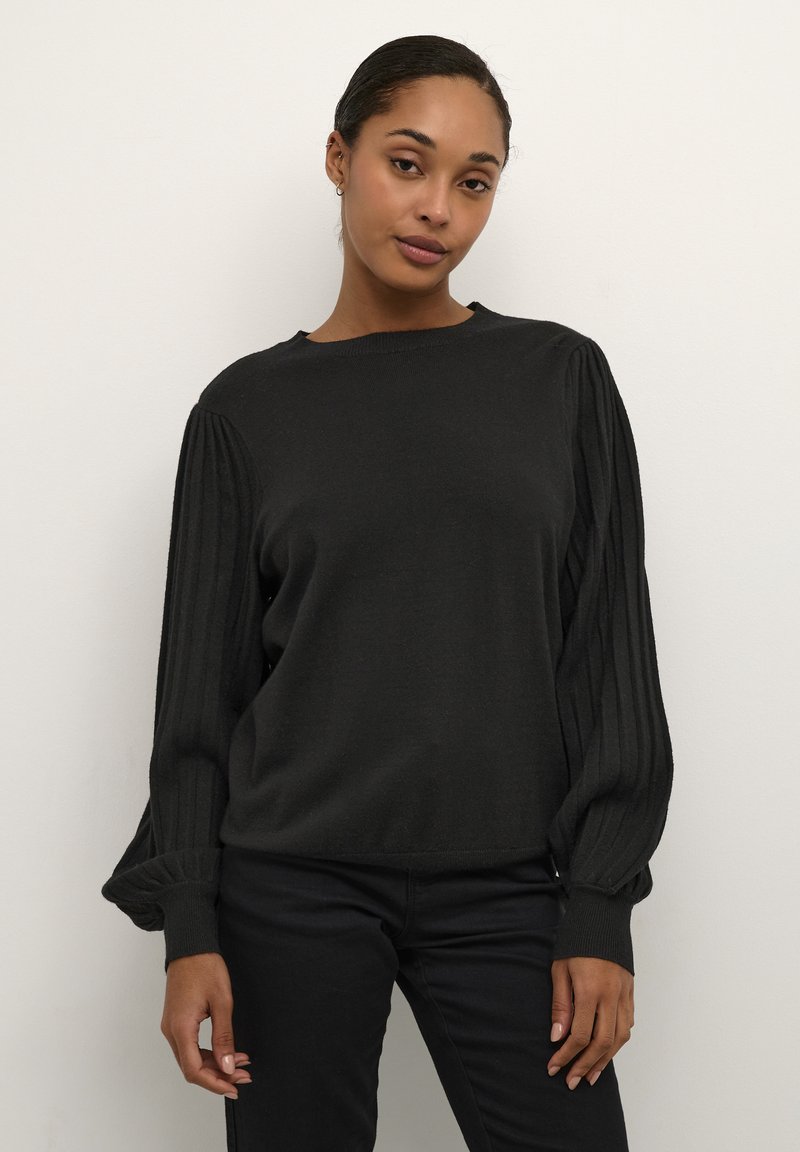 Pull en tricot noir avec des manches bouffantes côtelées et un col rond. Texture douce, coupe décontractée, et détails subtils aux poignets et à l'ourlet.