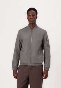Gray bomber jacket with a zipper front, two side pockets, and a zippered sleeve pocket. Smooth fabric, ribbed cuffs, and hem.