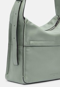 Borsa a spalla verde in pelle con chiusura zip, design piatto, dettagli cuciti e tasca frontale. Bordi rifiniti in nero.