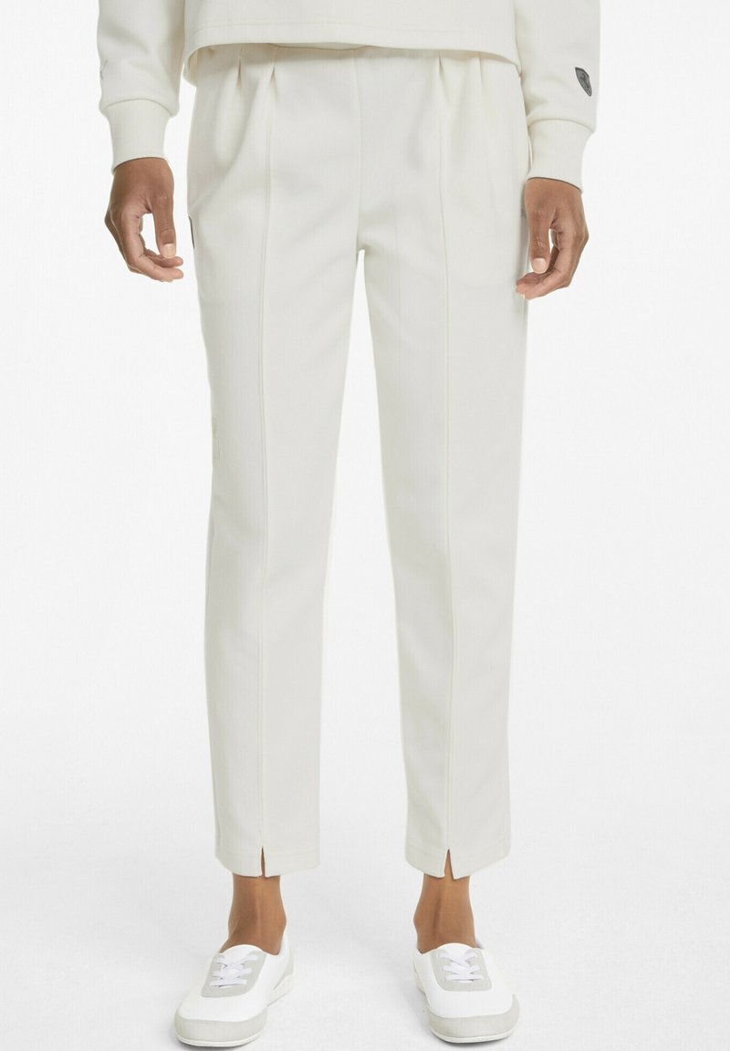 Vita skräddarsydda byxor med veck, slim fit och sidoklipp vid fållen, tillverkade av textilier med struktur, matchade med vita sneakers.