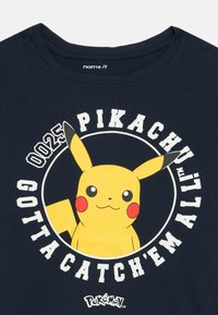 Tamnoplavi pamučni majica s grafikama Pikachu. Natpis glasi "025 PIKACHU Gotta Catch 'Em All!" u bijeloj boji s kružnim dizajnom.