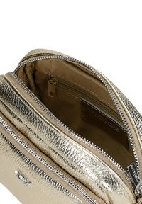 Metalická zlatá crossbody taška s texturovaným povrchem, která má dva zipové oddíly a béžovou podšívku.