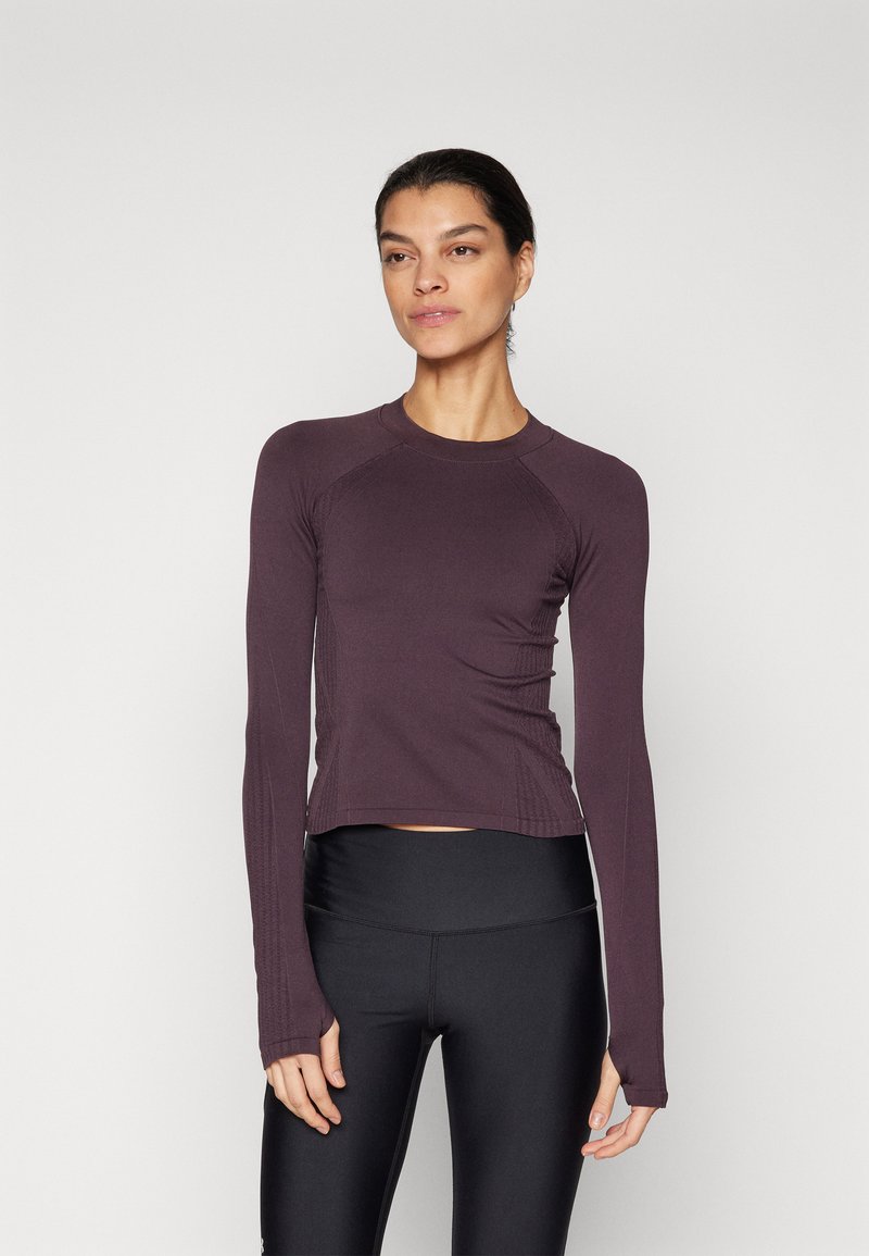 Långärmad tränings tröja i djupt lila, med ribbat mönster och tumhål vid ärmarna. Matchad med högmidjade svarta leggings.