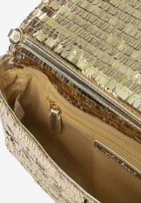 Borsa a tracolla dorata in metallo con superficie texturizzata e paillettes. L'interno include un compartimento principale e una tasca con zip.