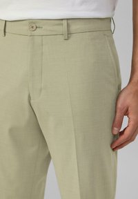 Helle grüne Hose aus strukturiertem Stoff. Mit einem Knopfverschluss, Gürtelschlaufen und einer Seitentasche. Glattes, gerade geschnittenes Design.