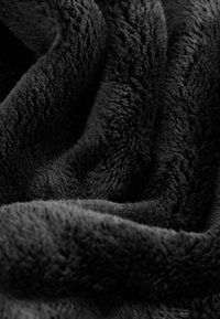 Black, plush blanket with a soft, textured surface, exhibiting a thick fabric with folded, wavy patterns throughout.