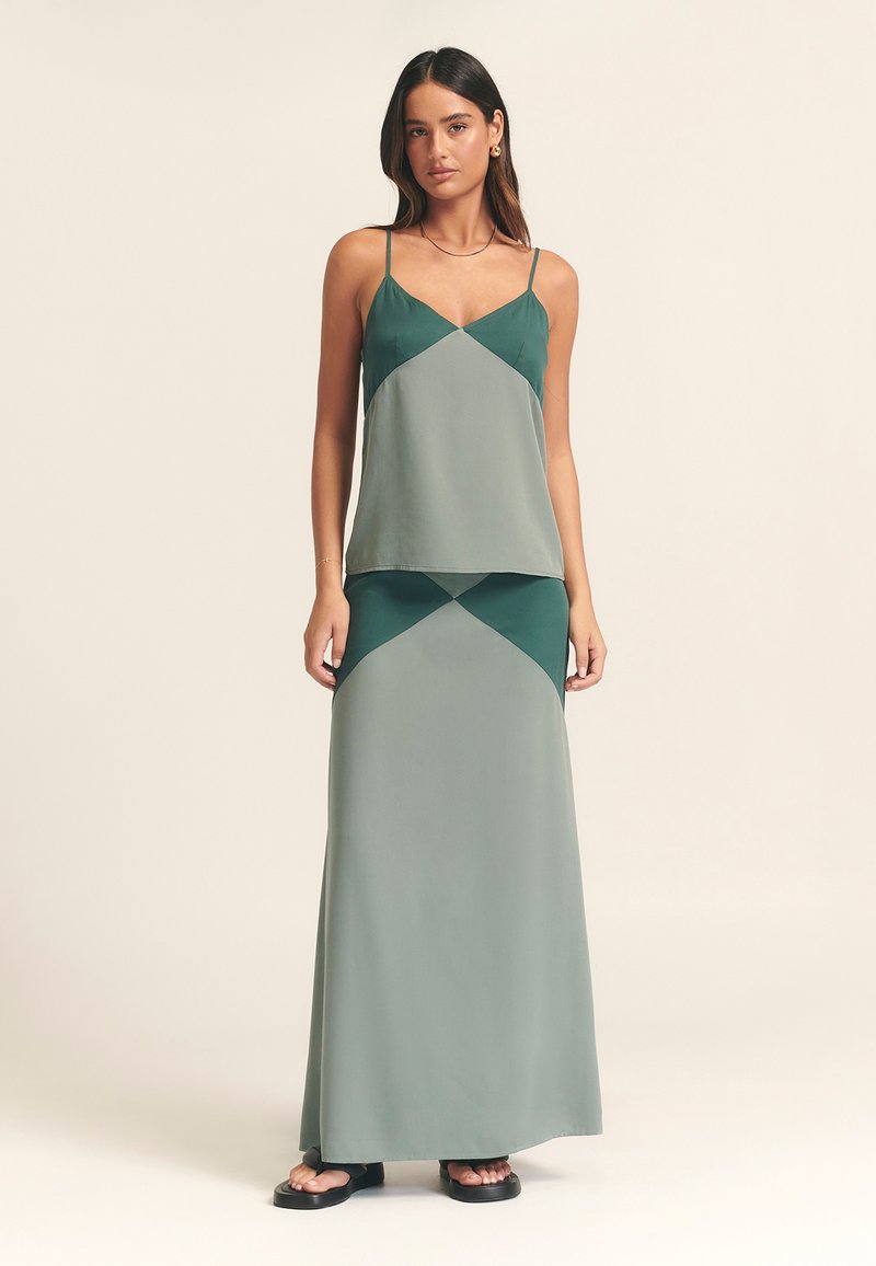 To-delt sæt med en ærmeløs top i grønne og grå farveblokke samt en matchende lang nederdel med en flydende silhuet.