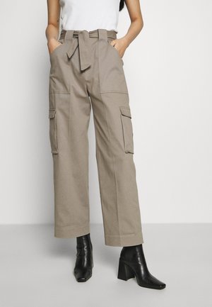 Pantaloni cargo beige con vita regolabile, gamba ampia e diverse tasche. Tessuto in cotone liscio con una vestibilità su misura, abbinati a stivali neri con tacco.