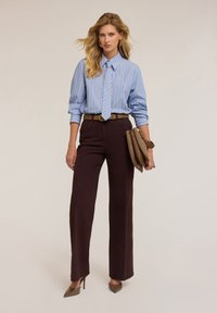 Pasiasta niebiesko-biała koszula zapinana na guziki, w połączeniu z brązowymi spodniami o wysokim stanie. Brązowy pasek i torebka, do tego beżowe szpilki.