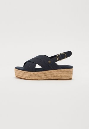Sandalo con zeppa blu navy con cinturini incrociati in tessuto, fibbia regolabile color oro e suola platform in juta intrecciata.