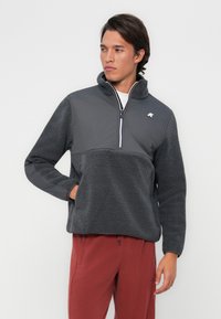 Pulloverjack in donkergrijs, met een fleece ondergedeelte en een glad bovenste deel, halve rits aan de voorkant en een hoge kraag.