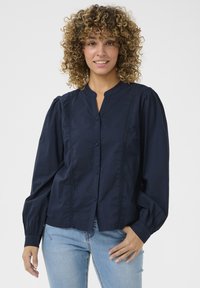 Navyblauwe blouse met knopen, gemaakt van textuurstof, met een staande kraag, pofmouwen en decoratieve kantafwerking aan de voorkant.
