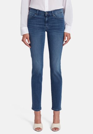 Jean en denim bleu avec une coupe slim, taille mi-haute et un léger délavage sur les cuisses. Comprend cinq poches et une fermeture à bouton classique.