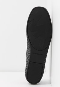 Baskets noires avec une tige en tissu gris texturé, présentant un motif géométrique et une semelle en caoutchouc noir solide avec des détails de logo.