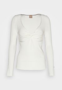 Haut blanc à manches longues en maille côtelée avec un nœud torsadé à l'avant et un décolleté profond en arrondi.