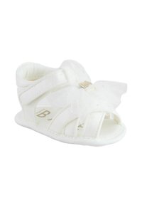 White sandal with a soft, mesh-like overlay and a decorative bow on the front. Features open design and adjustable straps.