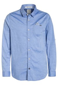Camisa de manga larga azul con un pequeño patrón de lunares, cierre de botones en la parte delantera y un bolsillo en el pecho con un sutil acento gráfico.