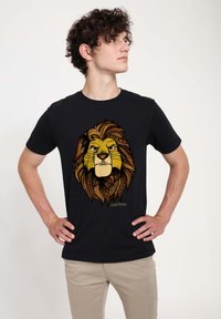 Sort t-shirt med et gyldent løvdesign, der har indviklede marmorede og gyldne mønstre. Designet er centreret og inkluderer teksten "LØVENS KONGE."