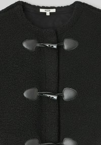 Veste en polaire noire avec col rond, trois fermetures à bascule avec accents en cuir, et une surface en tissu texturé. Taille S.