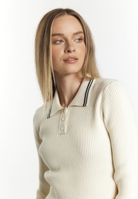 Crème geribbelde longsleeve polo met kraag, met marineblauwe strepen, vier knopen en een getailleerd silhouet.