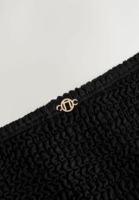 Tăietură din material negru cu un model texturat, având un detaliu din hardware circular auriu în partea de sus.