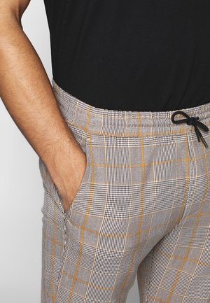 Graue und schwarze karierte Hose mit orangefarbenen Akzenten, mit elastischem Bund, Seitentaschen und lockerer Passform. Strukturierter Stoff.