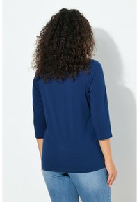 Granatowy top z rękawami do łokcia i okrągłym dekoltem, wykonany z miękkiego materiału, o luźnym kroju i gładkiej fakturze.