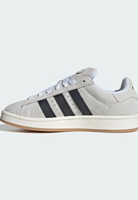 Sivi zamakteni tenisice s bijelim vezicama i gumenim potplatom, s tri crne pruge i glatkim jezikom. Ojačana prednja strana i minimalistički dizajn.