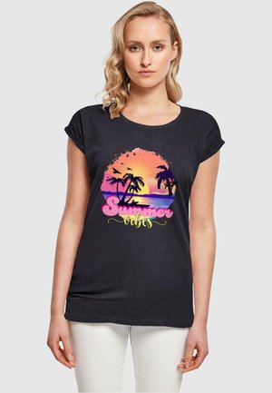 Svart T-skjorte med korte ermer som har et fargerikt solnedgangsdesign med palmtrær og teksten "Summer Vibes" i rosa og gult.