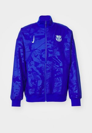 Giacca zip-up blu realizzata in tessuto liscio, con un motivo testurizzato e colletto alto. Presenta un logo del club e il baffo Nike.