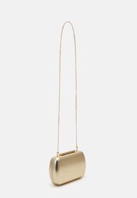 Pequeño bolso de mano rectangular de oro con una cadena larga y delgada, sobre un fondo blanco liso.