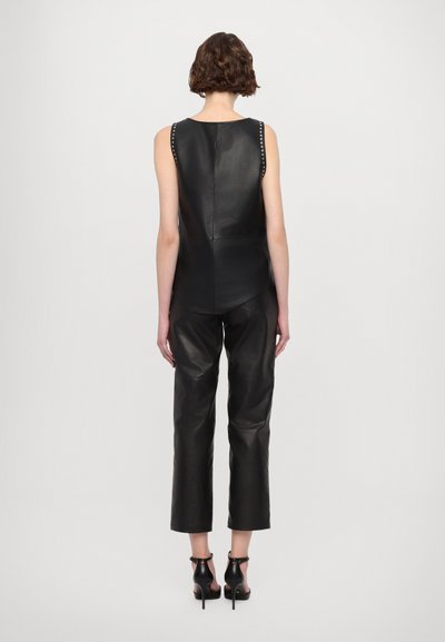Black leather sleeveless top with shoulder studs, paired with black leather cropped pants and open-toe black heeled mules.