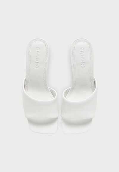 Paire de mules blanches à bout ouvert avec des larges brides et des semelles carrées, marquées "SANDRO" sur les semelles intérieures.