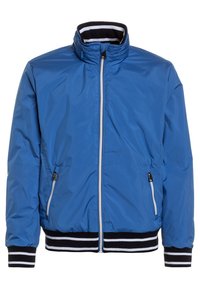 Giacca leggera blu con colletto alto, zip frontale e tasche laterali. Presenta polsini e orlo a coste rigate bianco e nero.