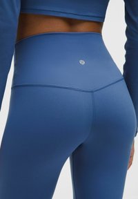 Modré legíny s vysokým pásom vyrobené z hladkého a elastického materiálu. Obsahujú jemné logo na zadnej strane a ploché švy pre pohodlie.