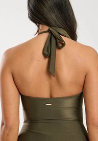 Maillot de bain olive vert à encolure halter avec un noeud noué dans le dos. Présente un tissu lisse et brillant ainsi qu un petit accent métallique dans le dos.