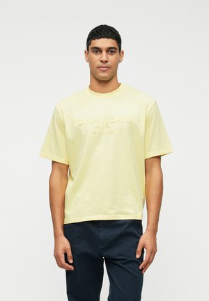Sárga pamut póló laza szabással, kerek nyakkal és hímzett "TOMMY JEANS" logóval az elülső részen. Rövid ujjak, sima dizájn.