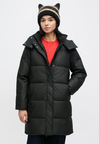 Čierny prešívaný kabát s predným zipsom a patentnými gombíkmi, s odnímateľnou kapucňou, prešívaným dizajnom a bočnými vreckami. Dopĺňa ho pletená čiapka.