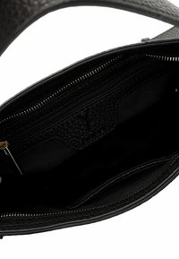 Intérieur d'un sac à main en cuir noir texturé, avec une poche zippée, une doublure en tissu et plusieurs poches plaquées pour l'organisation.