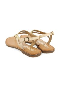 Sandalias planas beige con diseño de tira en T, que cuentan con un acento de hebilla y una plantilla acolchada texturizada. Material suave con un ligero cosido.