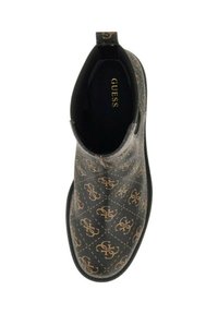 Scarpa nera slip-on con motivo del logo marrone di Guess su tutta la superficie, dotata di un manico sul retro e con "GUESS" stampato in oro all'interno della scarpa.