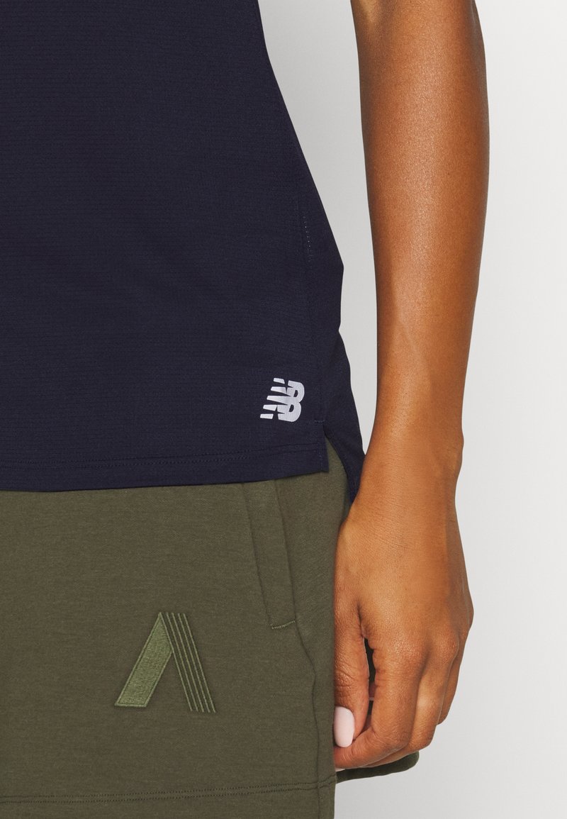 Top atlético azul marino con tejido texturizado, con un logo blanco en el dobladillo, combinado con pantalones cortos verde oliva que presentan un diseño cosido.
